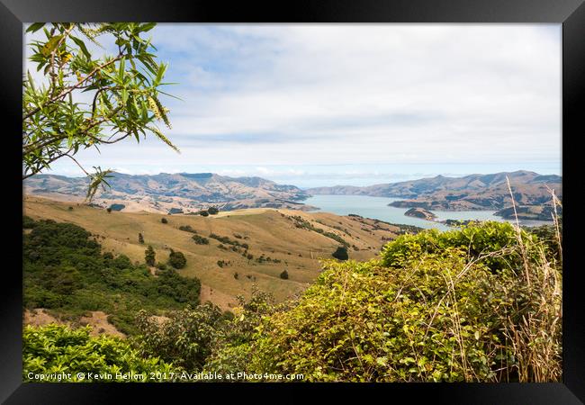 View across rolling hills to the natural harbour o Framed Print by Kevin Hellon