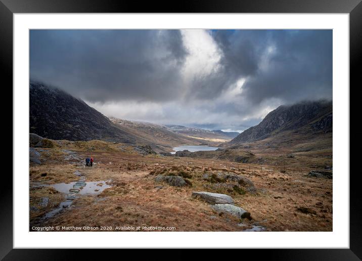 Hikers in Ogwen Valley Winter landscape with snowcapped Pen Yr Ole Wen and Tryfan mountains Framed Mounted Print by Matthew Gibson