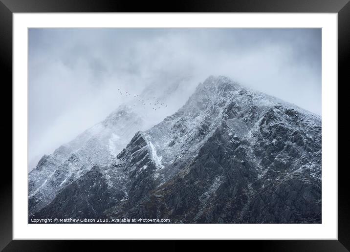 Stunning detail landscape images of snowcapped Pen Yr Ole Wen mountain in Snowdonia during dramatic moody Winter storm with birds flying high above Framed Mounted Print by Matthew Gibson