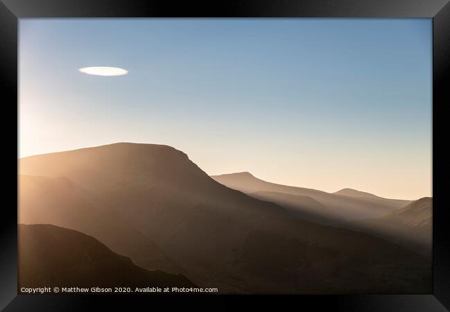 Beautiful Autumn Fall landscape image of sun beams lighting up small area of mountain side in Lake District whilst rest of area is in darkness with Robinson and Dale Head in background Framed Print by Matthew Gibson