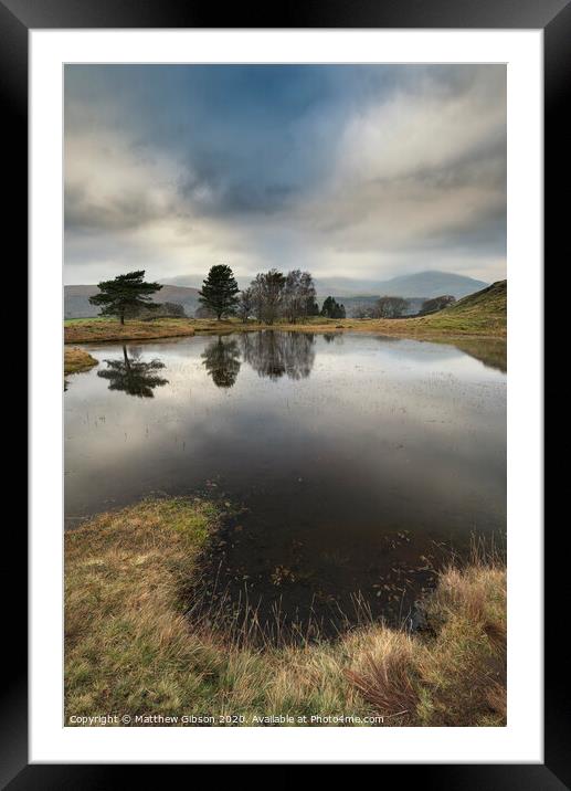 Stunning landscape image of dramatic storm clouds over Kelly Hall Tarn in Lake District during late Autumn Fall afternoon Framed Mounted Print by Matthew Gibson