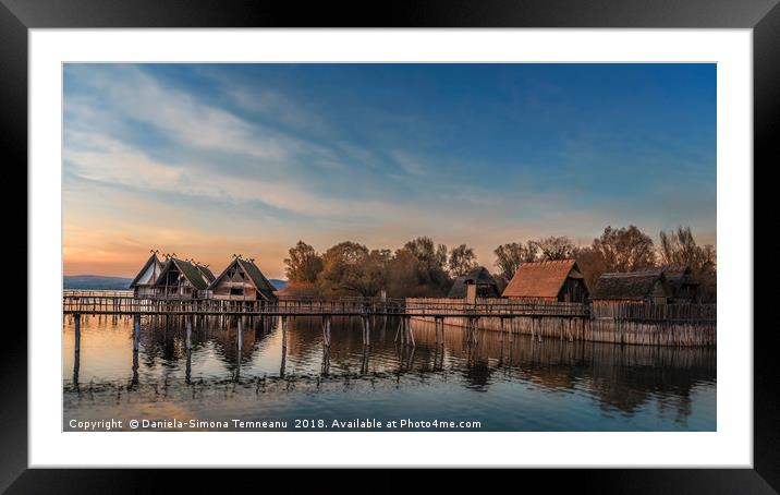 Huts and bridge over water at sunset Framed Mounted Print by Daniela Simona Temneanu