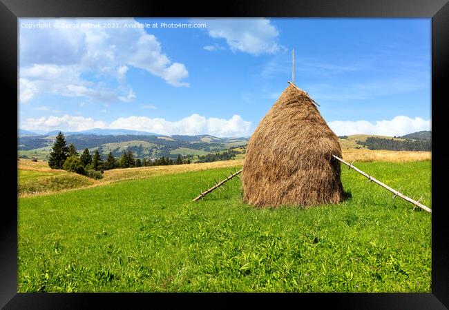 Haystack in the Carpathians on a green meadow against the backdrop of mountain hills. Framed Print by Sergii Petruk