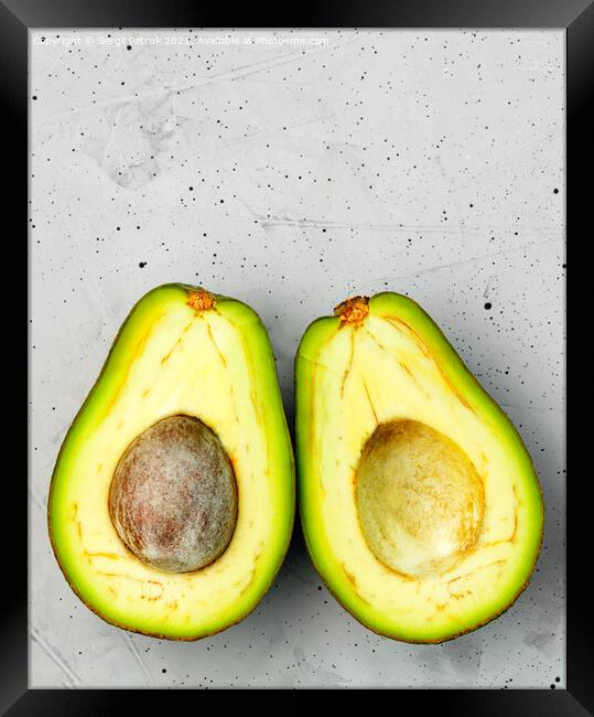 Avocado, cut in half, one slice with a core, on a gray concrete background, top view. Framed Print by Sergii Petruk