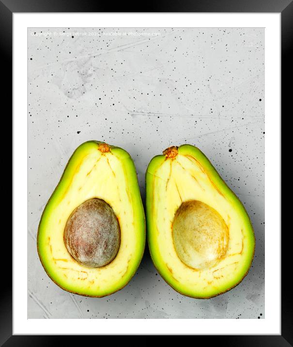 Avocado, cut in half, one slice with a core, on a gray concrete background, top view. Framed Mounted Print by Sergii Petruk