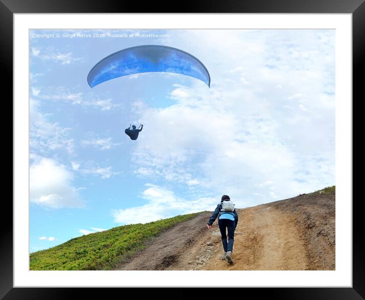 A young woman climbs up a mountain to meet a paraglider hovering in the air Framed Mounted Print by Sergii Petruk