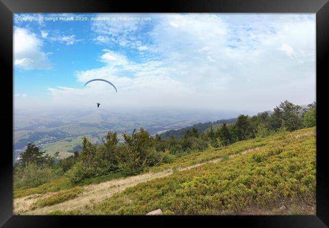 A flying paraglider against the blue sky, in the morning fog of the Carpathian Mountains Framed Print by Sergii Petruk