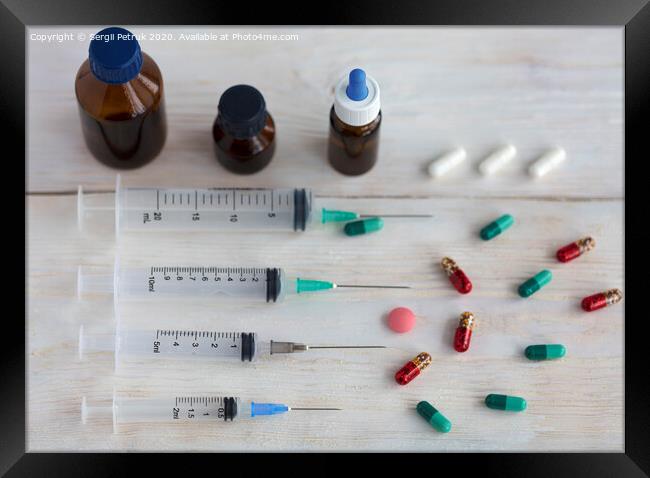 Syringes and capsules, medical ampoules and tablets on a white wooden table. Framed Print by Sergii Petruk