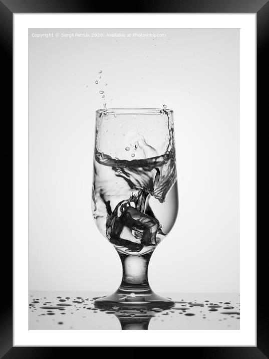 An ice cube falls into a glass glass with water Framed Mounted Print by Sergii Petruk