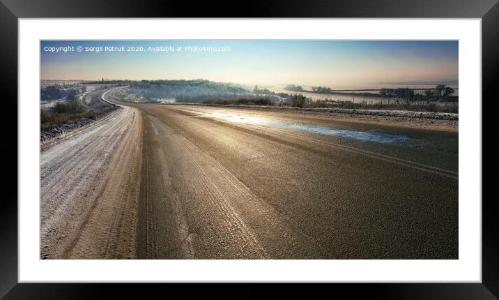 An old asphalt road is illuminated by sunshine in the winter morning. Framed Mounted Print by Sergii Petruk