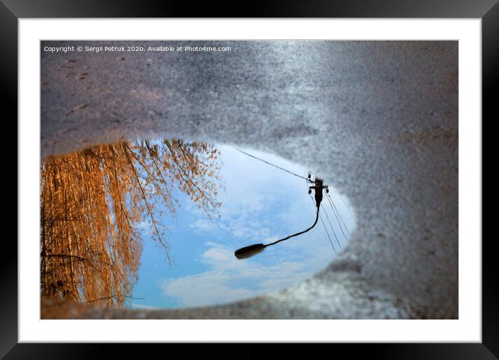 Reflection of the sky, the silhouette of a street lamp and a tree sunlit in a puddle on asphalt. Framed Mounted Print by Sergii Petruk