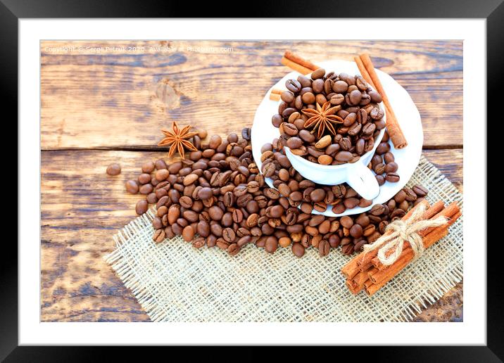 Grain coffee in a cup on a wooden background. Cinnamon on a napkin and tied with string. Anise stars complement the aroma of coffee. Framed Mounted Print by Sergii Petruk