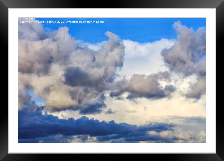 Storm clouds gather in a pile closing off a blue sky Framed Mounted Print by Sergii Petruk