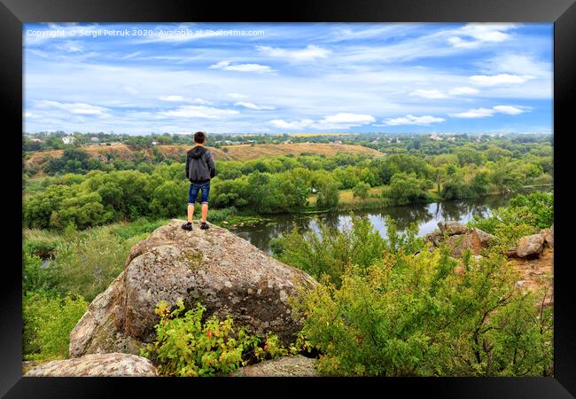 A teenager stands on top of a large stone boulder on the banks of the Southern Bug and looks into the distance. Framed Print by Sergii Petruk