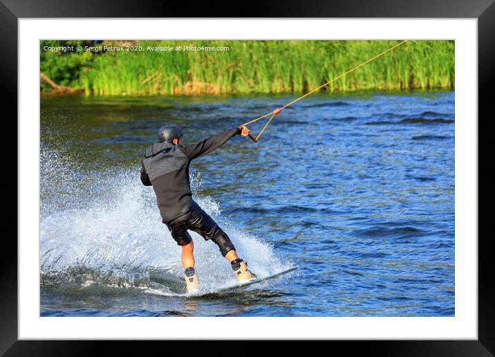A wakeboarder rushes through the water at high speed along the green bank of the river. Framed Mounted Print by Sergii Petruk