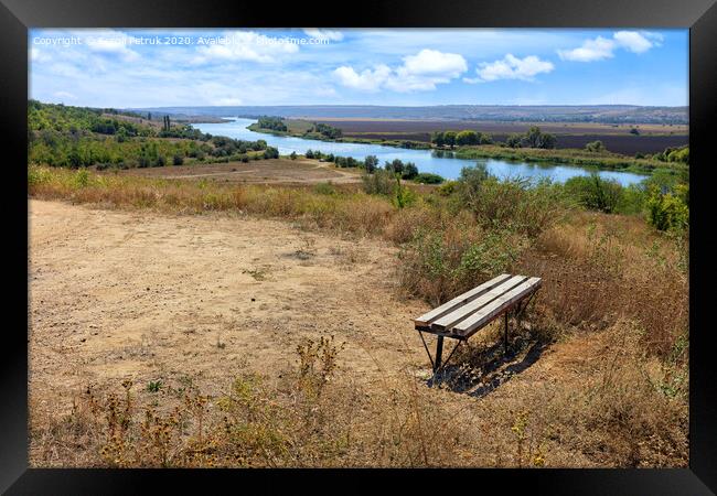 View of a wooden bench on a high river bank on a bright autumn day. Rural autumn landscape. Framed Print by Sergii Petruk
