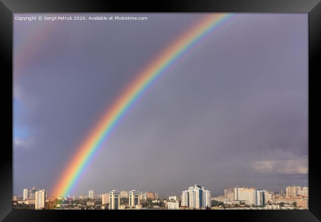 A large bright rainbow in the gray sky above the city after the last thunderstorm. Framed Print by Sergii Petruk
