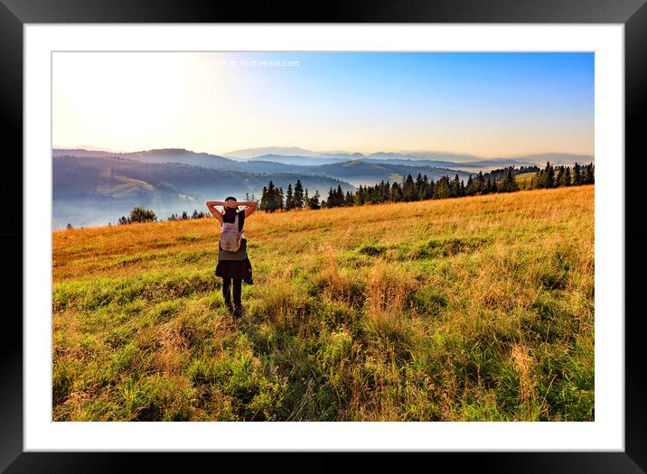 Young woman inhales the aroma of wild herbs and flowers at sunrise on a hilltop in the Carpathians. Framed Mounted Print by Sergii Petruk