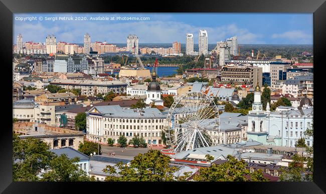 The landscape of the summer city of Kyiv overlooking the old district of Podil with a Ferris wheel and a bell tower with a gilded dome, the Dnipro River and many city buildings. Framed Print by Sergii Petruk