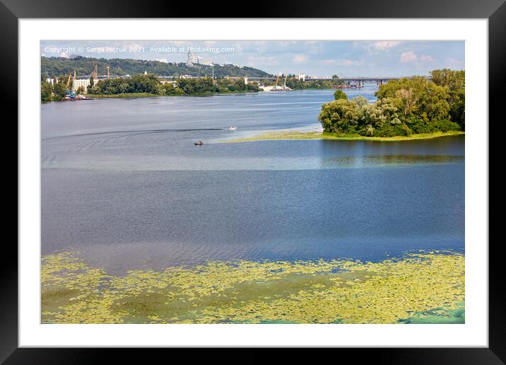 The picturesque natural landscape of the Dnipro River in the middle of summer with river lilies floating on the water in the foreground. Framed Mounted Print by Sergii Petruk