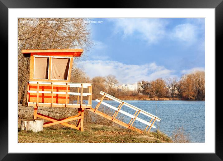 On the bank of the river with bare autumn bushes without leaves stands a lonely wooden house of lifeguards and is illuminated by the rays of the bright autumn sun. Framed Mounted Print by Sergii Petruk