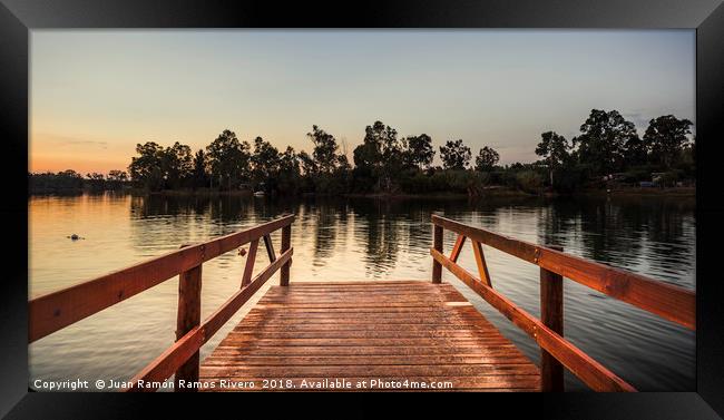 Reddish wooden pier over the lake with calm waters Framed Print by Juan Ramón Ramos Rivero