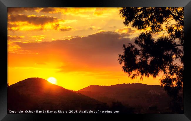 Sunset sun behind the mountain with orange sky Framed Print by Juan Ramón Ramos Rivero