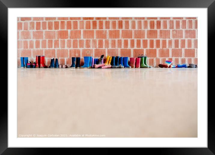 Rubber rain boots on the floor at the entrance to a college clas Framed Mounted Print by Joaquin Corbalan