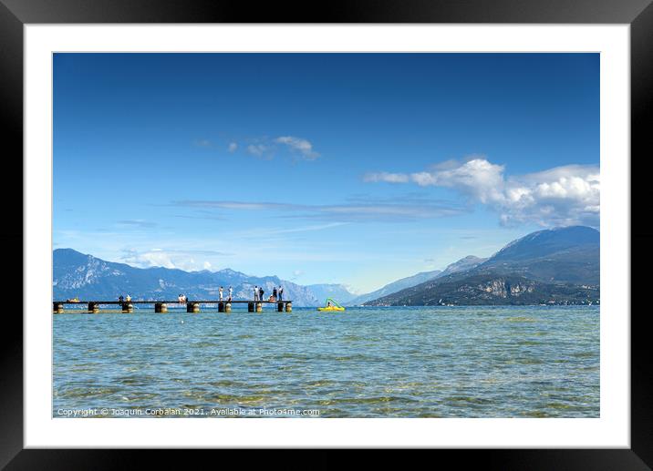 Calm water lake in Garda, Italy with a wooden walkway on a sunny Framed Mounted Print by Joaquin Corbalan