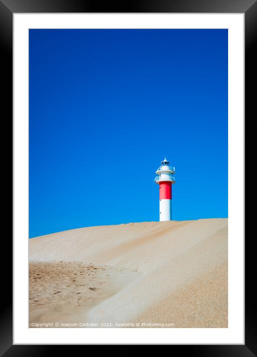A lighthouse seen from the sand dunes of a beach on a sunny day. Framed Mounted Print by Joaquin Corbalan