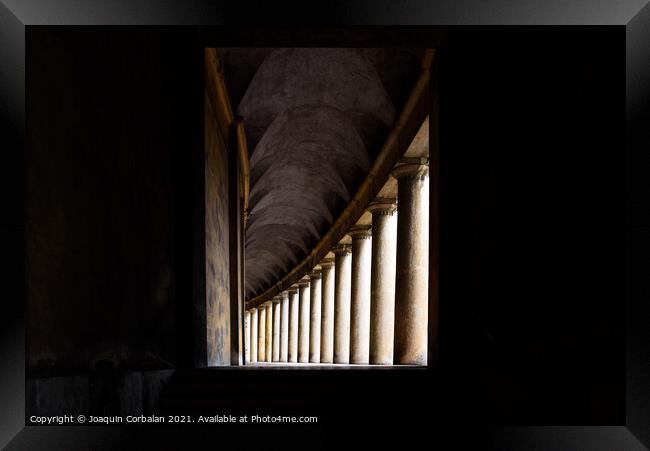 Hallway with monumental columns framed by the dark shadows of a  Framed Print by Joaquin Corbalan