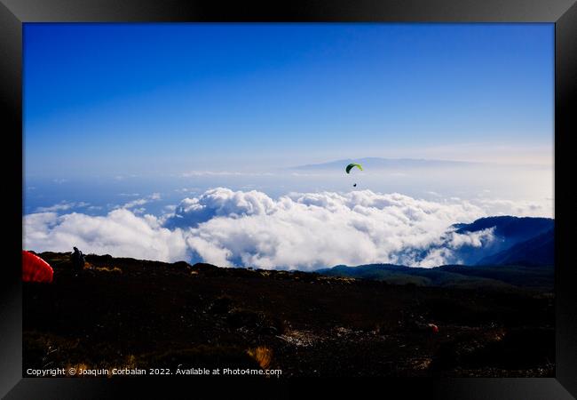 Paragliding above mountain peaks and white clouds during winter  Framed Print by Joaquin Corbalan