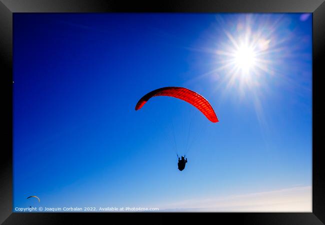 Paragliding above mountain peaks and white clouds during winter  Framed Print by Joaquin Corbalan