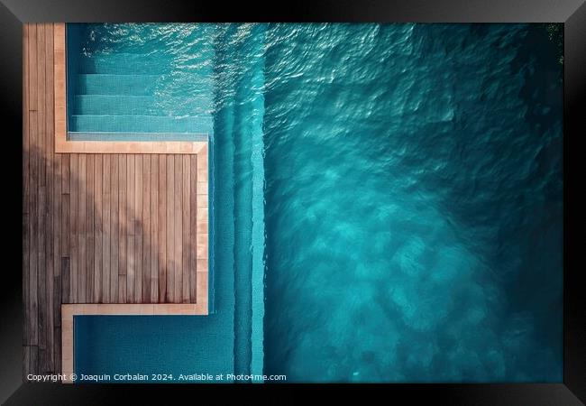 an aerial perspective of a swimming pool with a wooden deck. The pool is surrounded by the deck, providing ample space for relaxation and recreation. Framed Print by Joaquin Corbalan