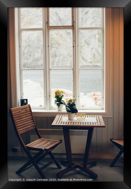 Empty table and antique wooden chairs near a window Framed Print by Joaquin Corbalan
