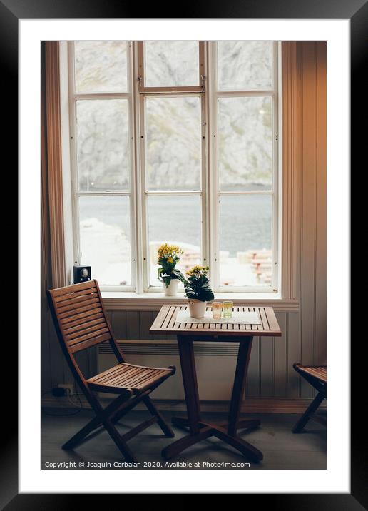 Empty table and antique wooden chairs near a window Framed Mounted Print by Joaquin Corbalan