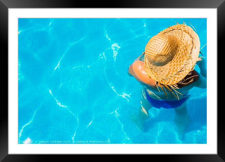 Woman in a pool with hat relaxed and rested. Framed Mounted Print by Joaquin Corbalan
