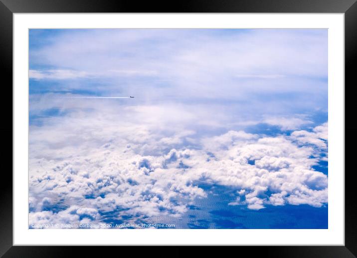 Plane of commercial flights crossing a sky of blue and white clouds seen from above, on the Mediterranean. Framed Mounted Print by Joaquin Corbalan