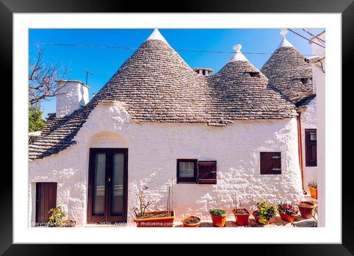 Houses of the tourist and famous Italian city of Alberobello, with its typical white walls and trulli conical roofs. Framed Mounted Print by Joaquin Corbalan