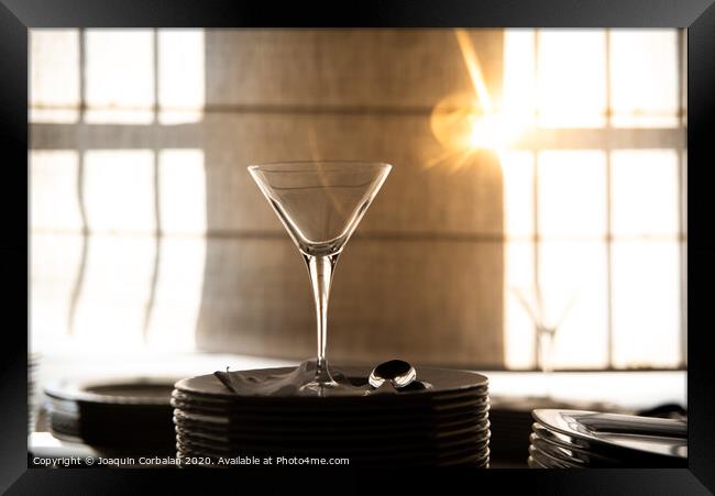 Empty glass cup with sun flares background in a restaurant. Framed Print by Joaquin Corbalan