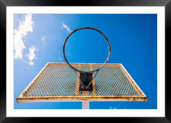 An old basketball basket outside a street with blue sky, copy space for text. Framed Mounted Print by Joaquin Corbalan