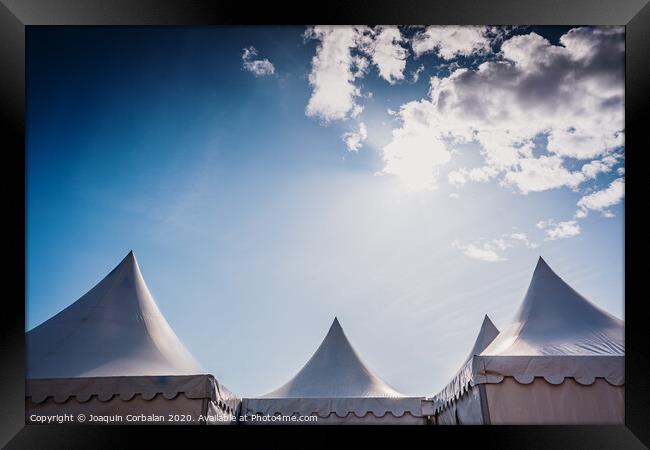 Peaks of three pyramidal white tents and blue sky background with space for advertisers text. Framed Print by Joaquin Corbalan