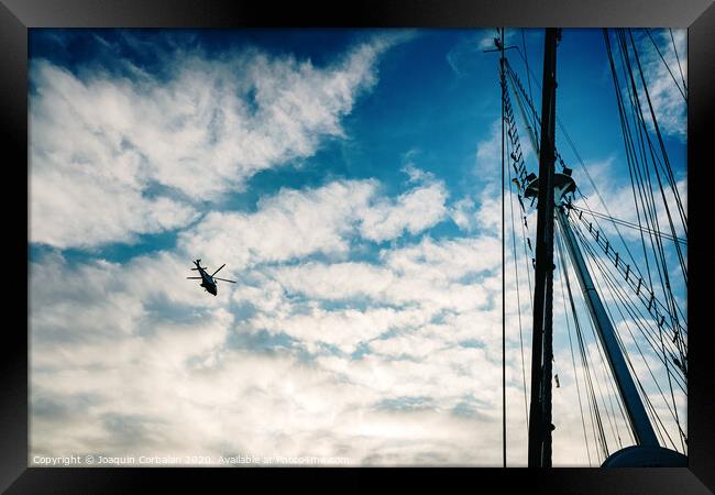  Rescue helicopter flying over a sailboat, seen from the sea. Framed Print by Joaquin Corbalan