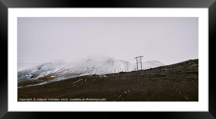 Poles of electricity in the middle of a snowy mountain to supply electrical power to remote villages. Framed Mounted Print by Joaquin Corbalan