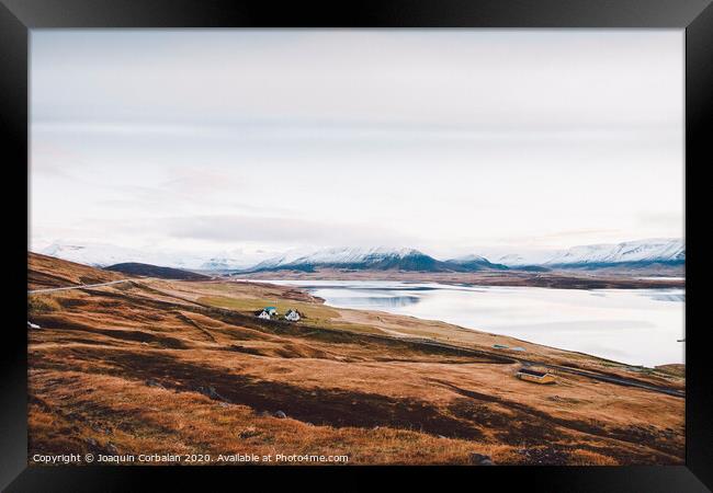 Village with farms in a rural area of the mountains of Iceland, with snowy mountains in the background. Framed Print by Joaquin Corbalan