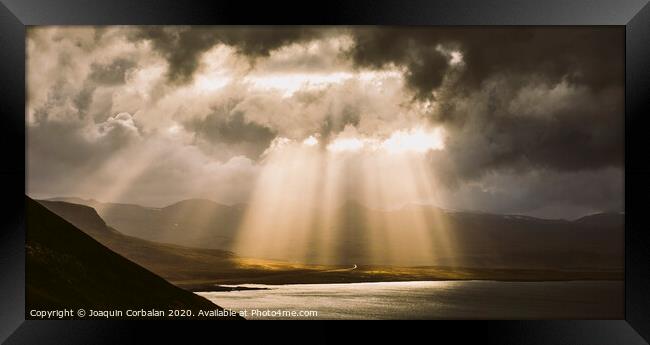 Sunbeams fall among the clouds in a lake between mountains. Framed Print by Joaquin Corbalan