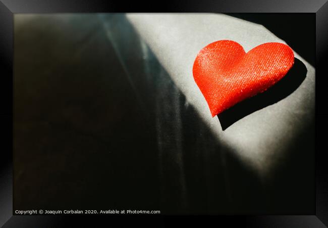 Red hearts isolated dark background illuminated by a ray of sun to use in the background, with a lot of empty space copy space. Framed Print by Joaquin Corbalan