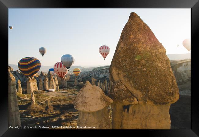 Goreme, Turkey - April 4, 2012: Hot air balloons for tourists flying over rock formations at sunrise in the valley of Cappadocia. Framed Print by Joaquin Corbalan