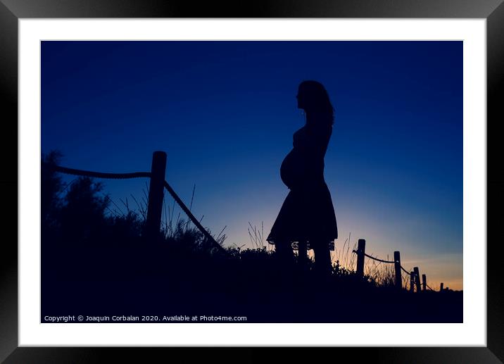Silhouette of pregnant woman at sunset with solid color background. Framed Mounted Print by Joaquin Corbalan