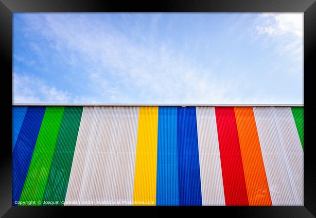 Facade with colored lines, against the blue sky in the background. Framed Print by Joaquin Corbalan